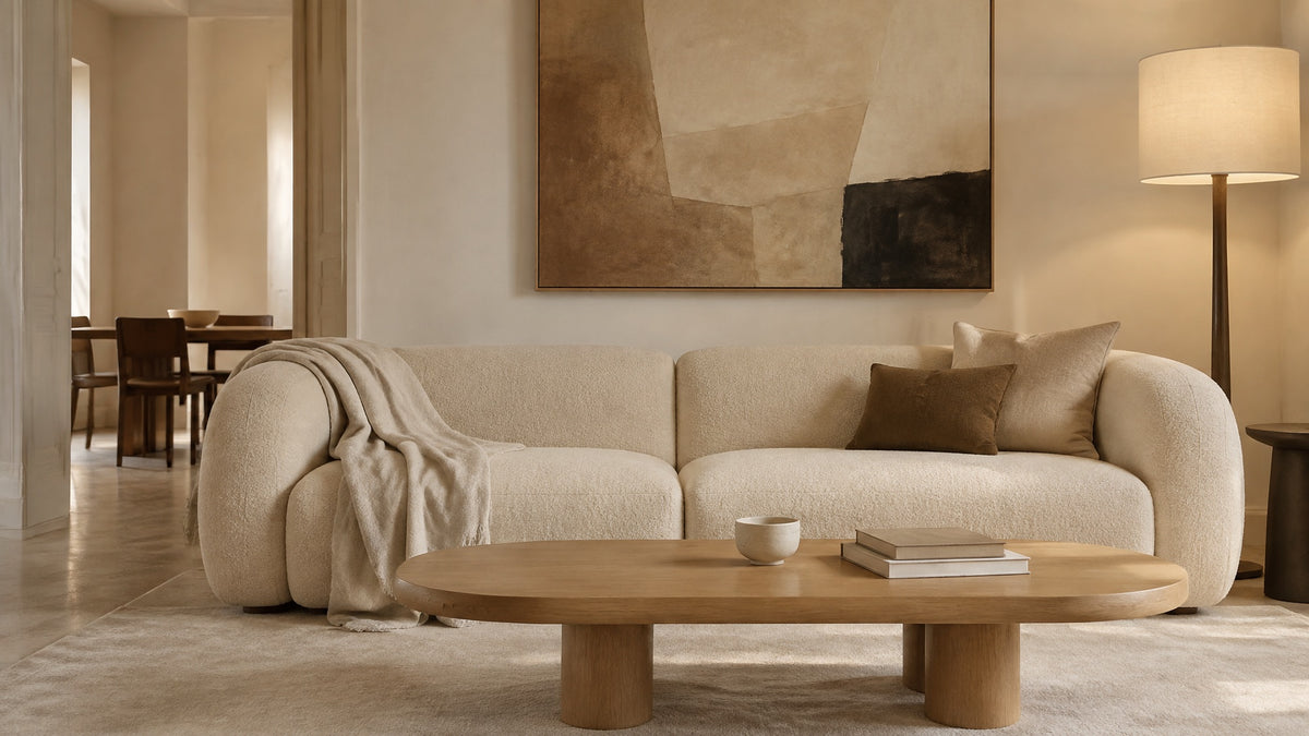 A calm cream living room with a curved sofa and a low oak coffee table in soft daylight